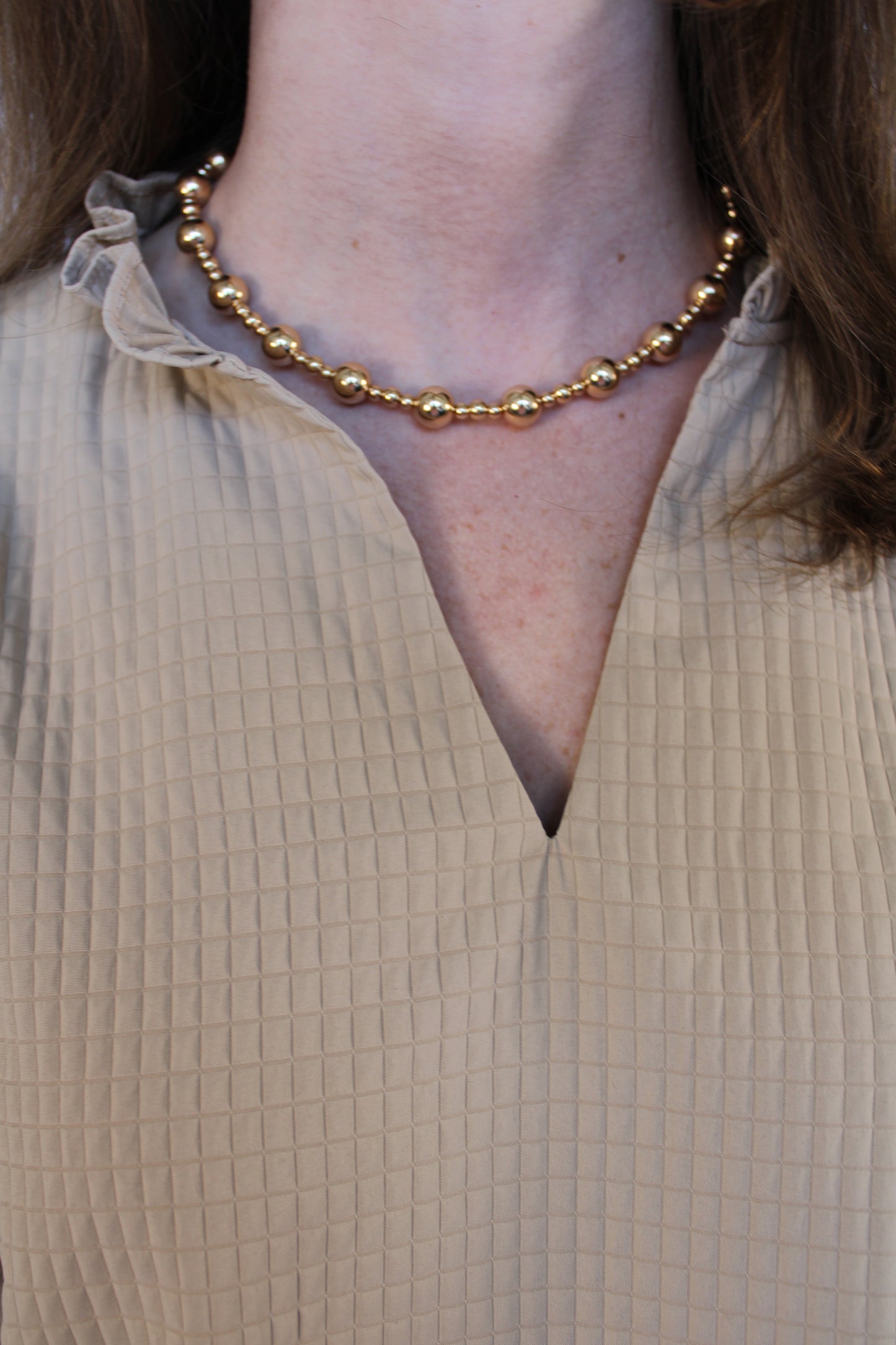 Close-up of a person's foot with a gold anklet on a textured surface