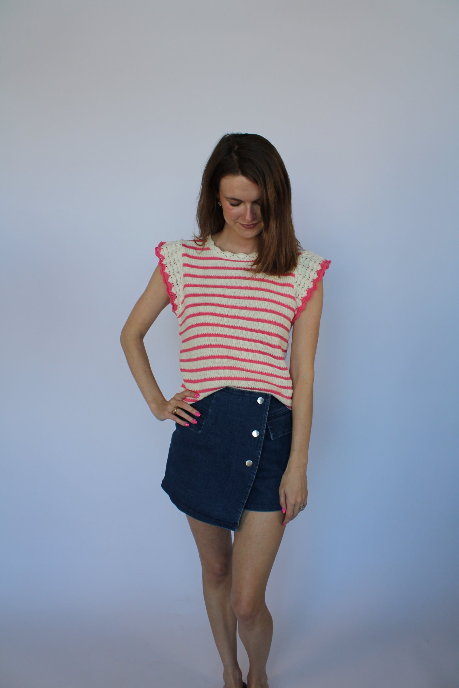 Woman wearing a red and white striped shirt and denim skirt against a plain background