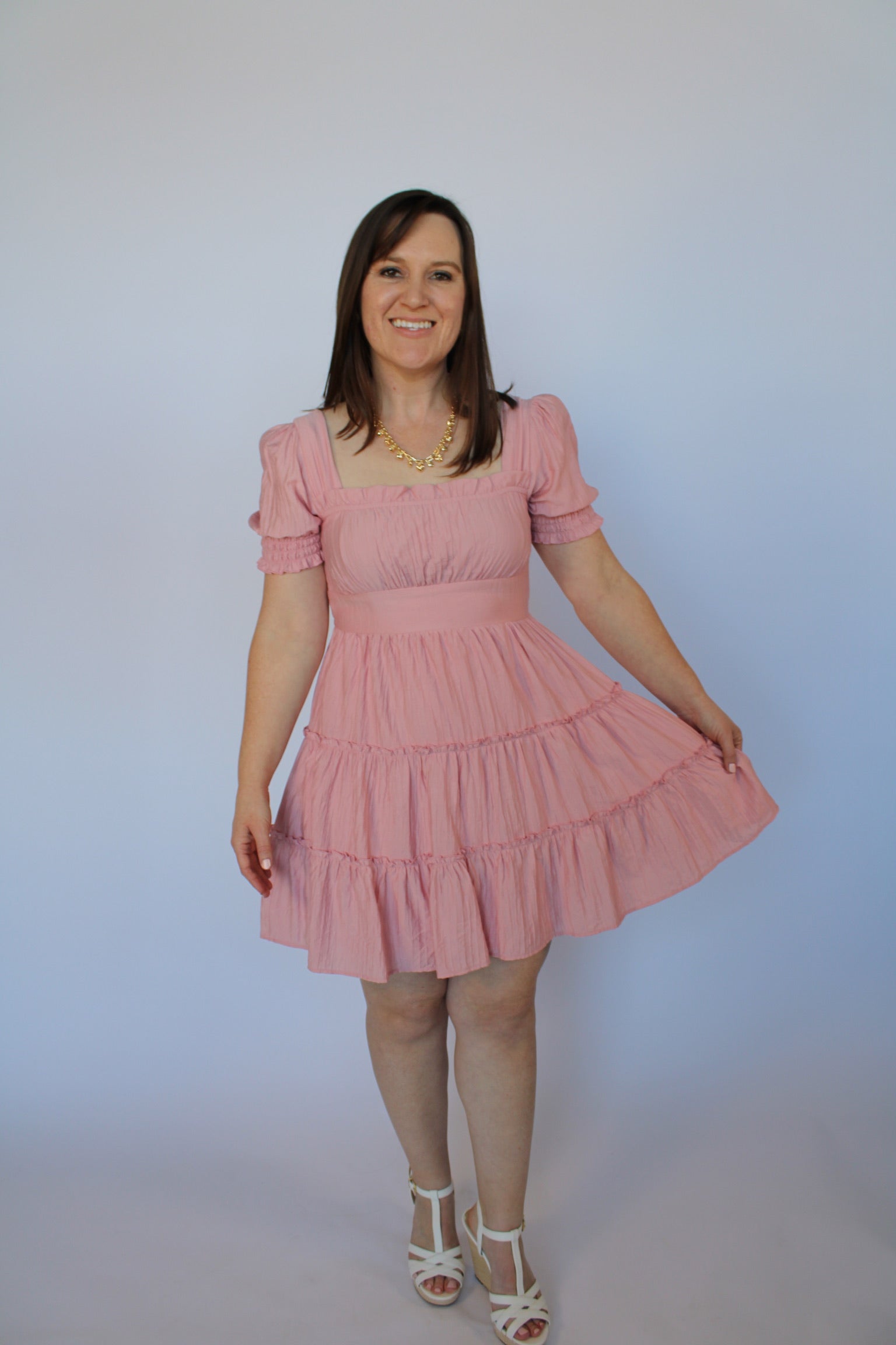 Woman wearing a pink dress against a plain background