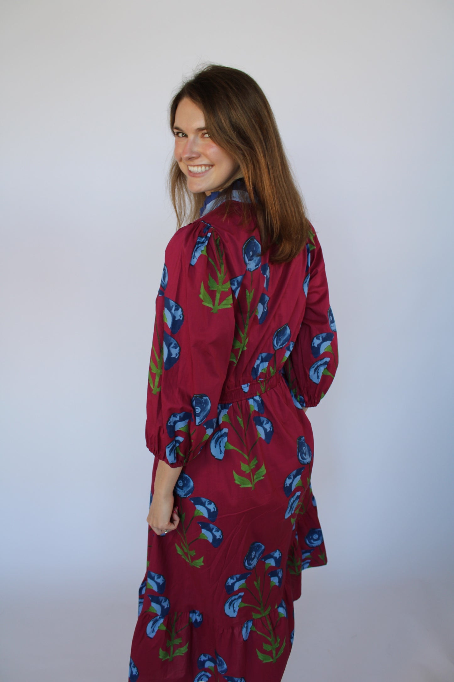 Woman wearing a red floral dress against a white background