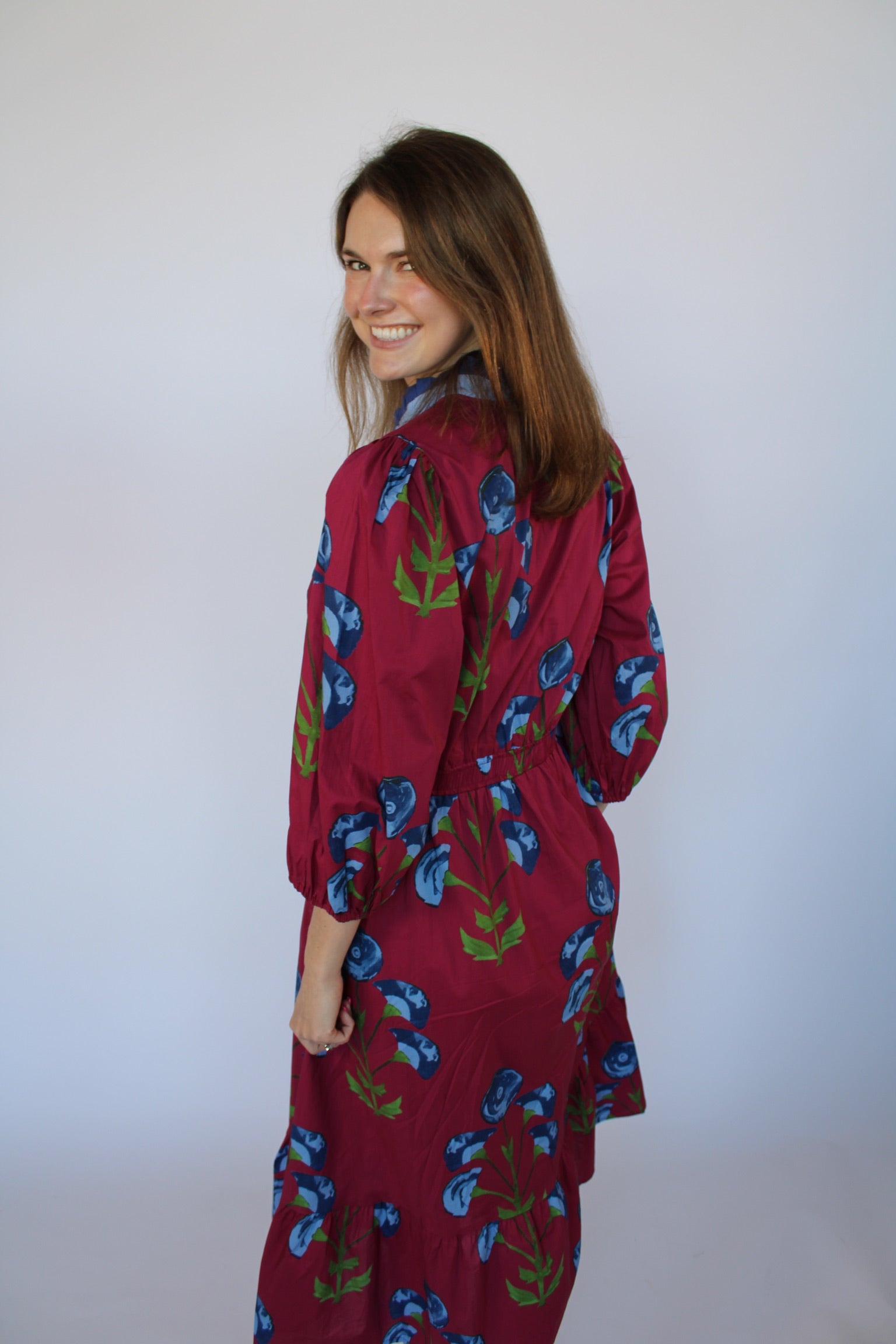 Woman wearing a red floral dress against a white background