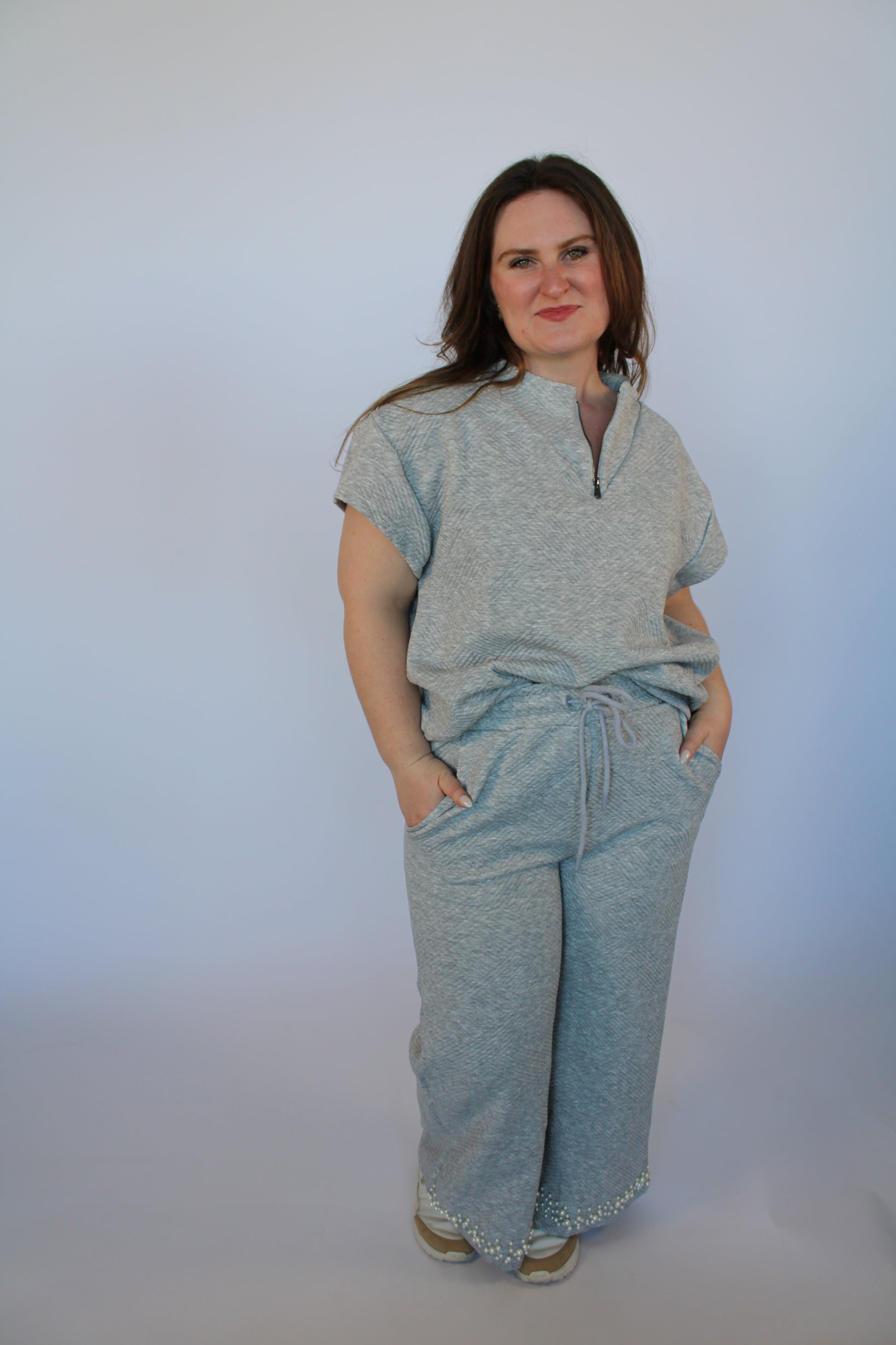 Woman wearing a light gray outfit on a white background