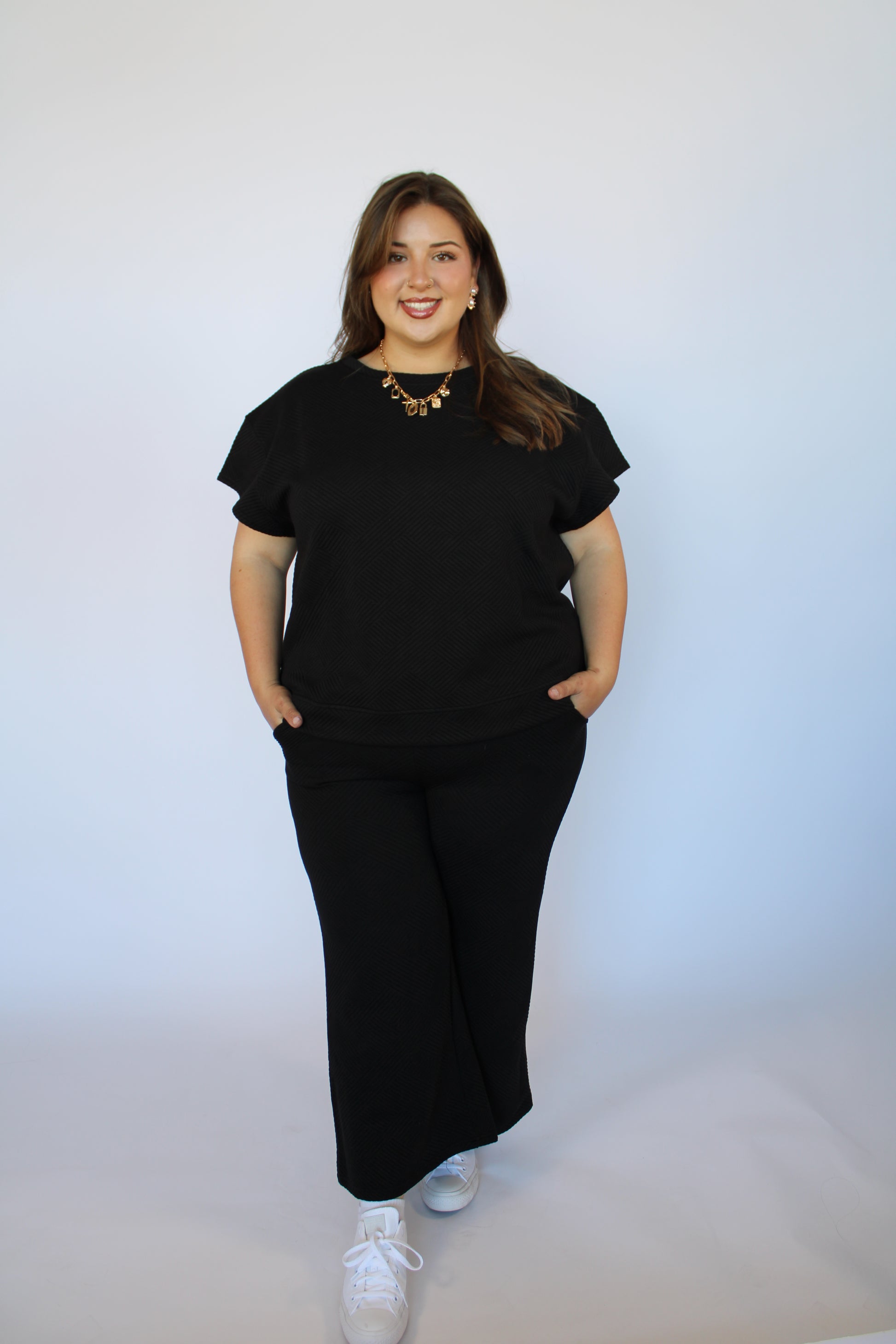 Person wearing a black outfit on a plain background
