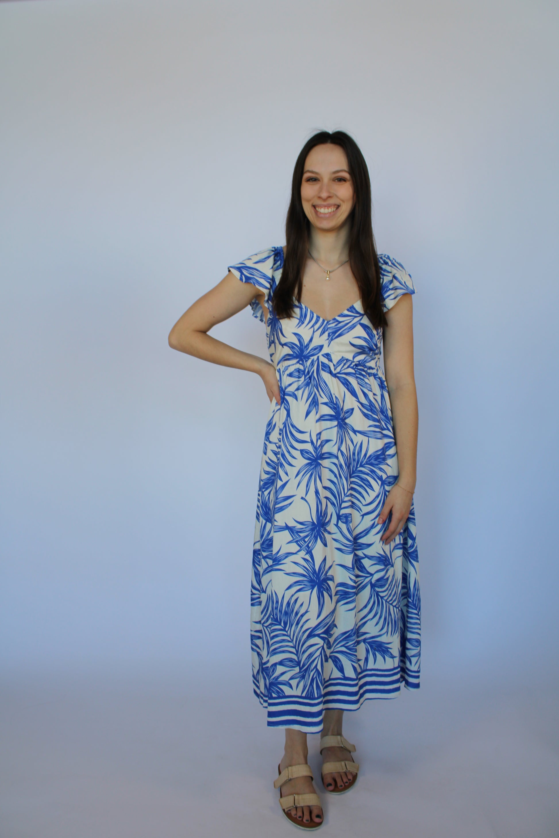 Woman wearing a blue and white patterned dress on a plain background