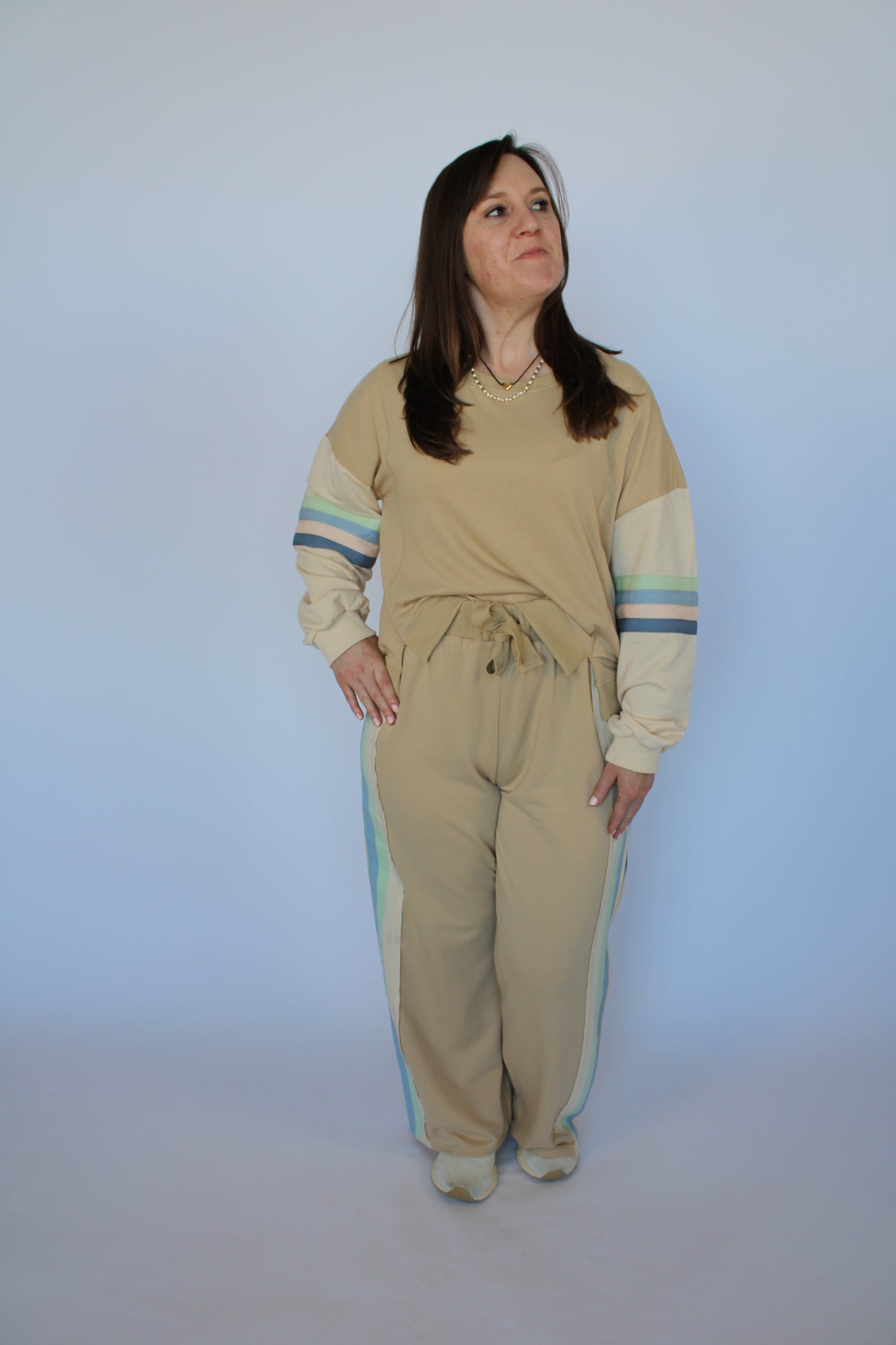 Woman wearing a beige outfit with blue stripes on a plain background