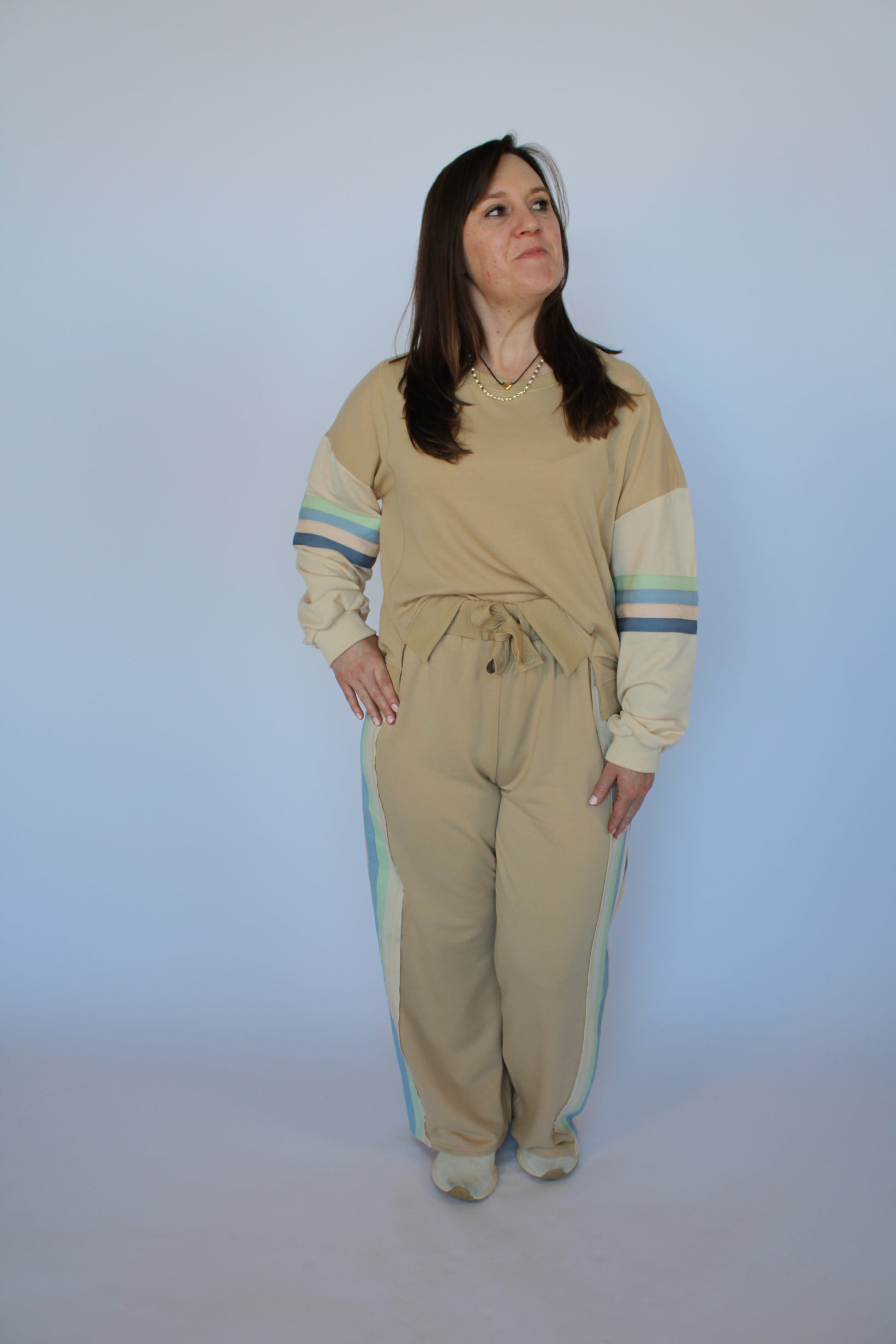 Woman wearing a beige outfit with blue stripes on a plain background