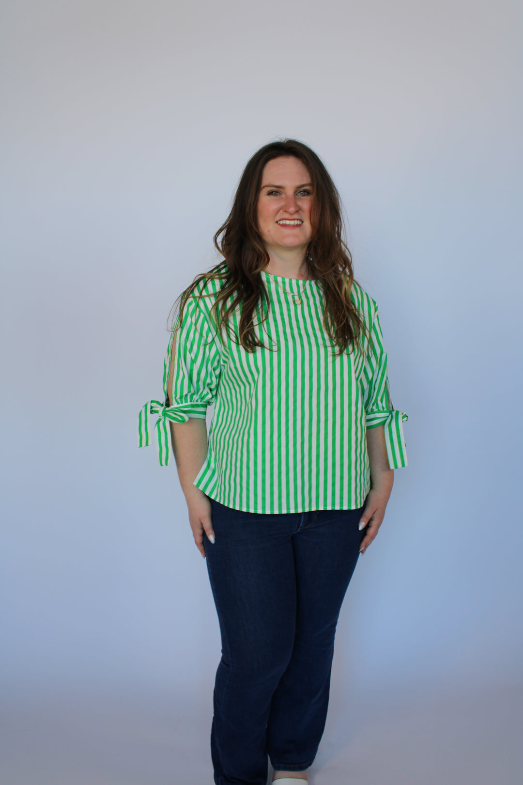 Person wearing a green and white striped shirt against a plain background